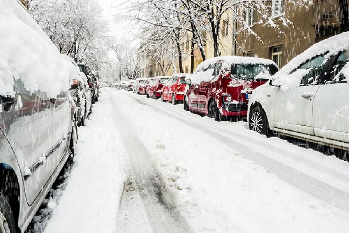 verschneite Straße mit parkenden Autos